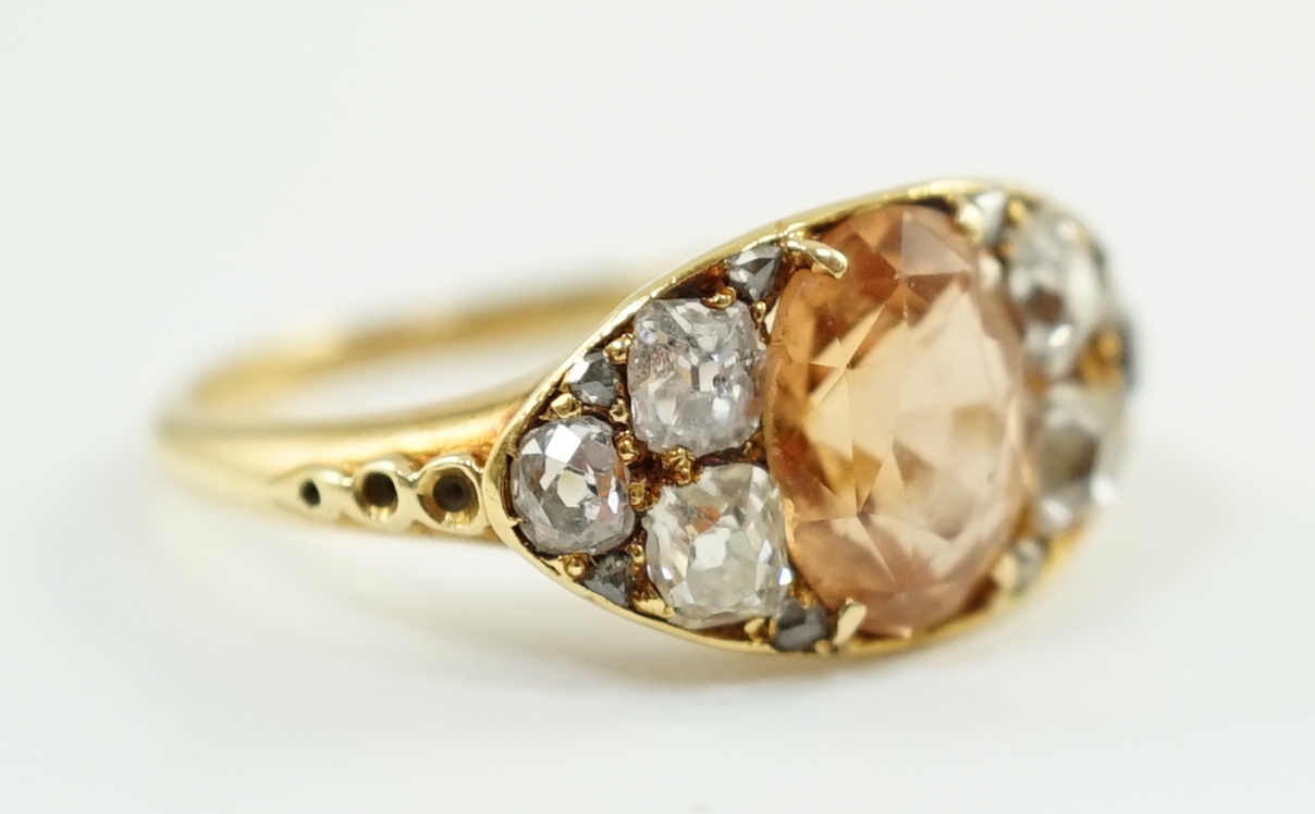 A 1940's gold and single stone oval cut orange topaz set ring, with six stone old mine cut diamond set shoulders